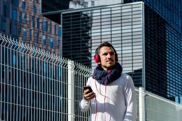 Attraktiv Ung Man Lyssnar Musik Med Hörlurar Medan Håller Mobiltelefon — Stockfoto