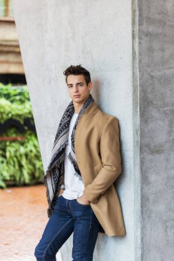 Dışarıda duran ve duvara yaslanan şık ve yakışıklı genç adamın portresi..