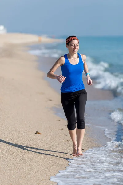年轻女子在海滨沙滩上奔跑 — 图库照片