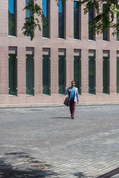 Businessman Walking Next Office Buildings While Holding Shoulder Bag — Stock fotografie