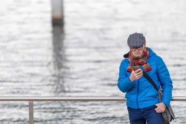 Senior Man Wearing Eyeglasses Leaning Railing Seafront While Using Smartphone — Stock fotografie