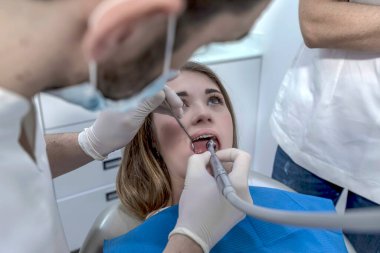 Erkek dişçi, dişçi koltuğunda dişçi dişlerini inceliyor. Diş Kliniği