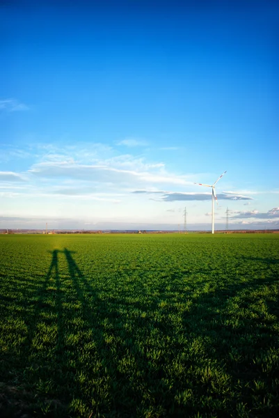 Landskap med vindkraftverk och skuggor av människor — Stockfoto