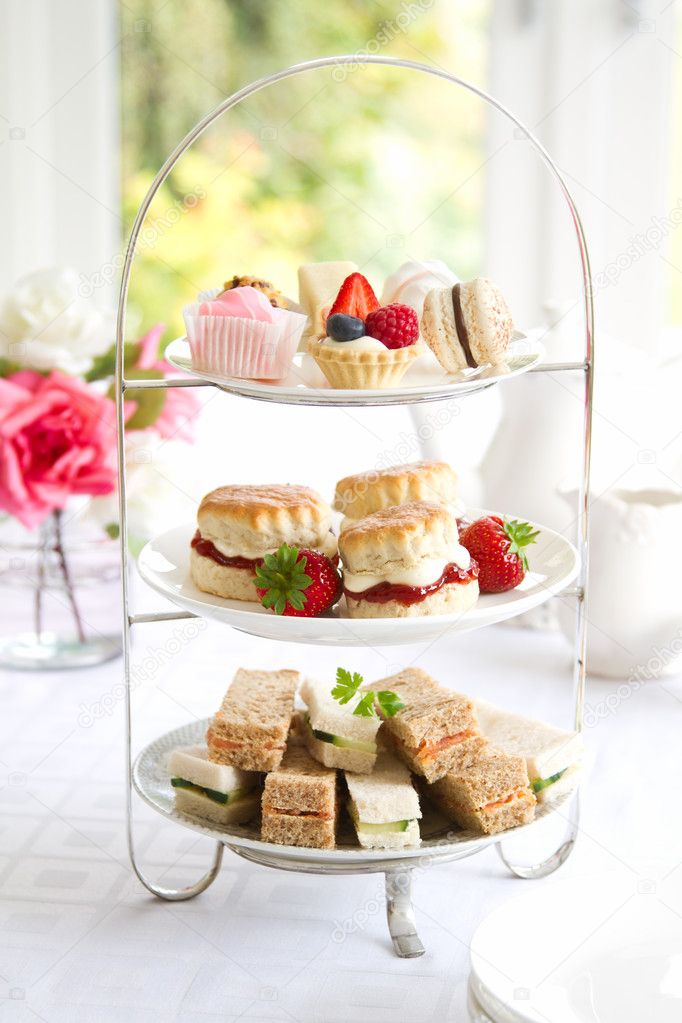 A photo of a tiered cake stand with sandwiches, scones, cakes and strawberries on different tiers