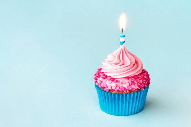 Doğum günü pastası çizgili doğum günü mumu ve mavi arka planda pembe serpiştirilmiş