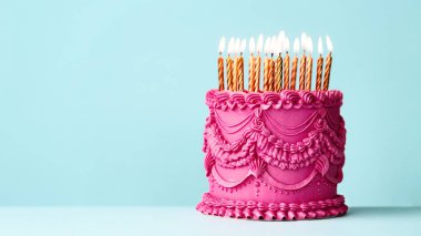 Fancy pink birthday cake with vintage style buttercream frills and ruffles and gold birthday candles against a blue background clipart