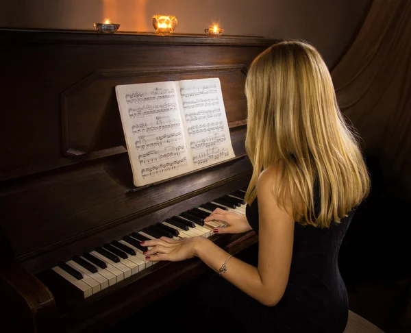 Menina tocando piano à luz de velas — Fotografia de Stock