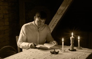 Genç yalnız başına umut dolu insan yüzü kutsal ilahi İsa koltuğu bak ve kutsal sayfayı aç. Antika İsrailli üzgün, yalnız, erkek çocuk. Koyu siyah, alev ışıklı, masa başı, kilise odası.