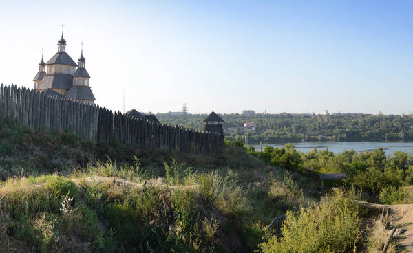 Fortified stockade settlement of Zaporizhzhya guard army troop 16-18 centuries. Panoramic view from Khortytsia island on broad Dnipro in quiet evening summertime sunset with space for text on blue sky