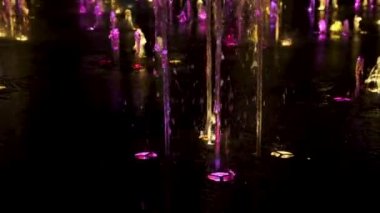 Geceleyin yavaş çekim rengarenk fıskiyeler ve çok renkli ışıklar. Su fışkırtan jetler şehir parkına ışık tuttu..