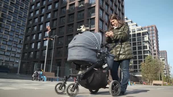 Junge Mutter Mit Neugeborenem Kinderwagen Mit Smartphone Beim Spazierengehen Der — Stockvideo