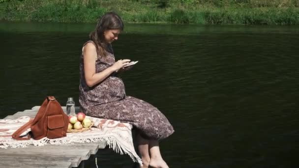 Těhotná Žena Sedí Bosá Dřevěném Molu Jezera Jablka Čte Knihu — Stock video