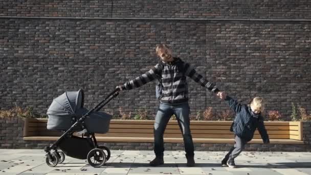 男子休产假的概念 滑稽疲惫的父亲坐在婴儿车里 在他的小儿子和新生儿之间徘徊 — 图库视频影像