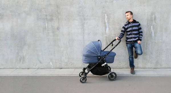 Moderner Vater Mit Neugeborenem Kinderwagen Steht Neben Grauer Betonwand Und — Stockfoto