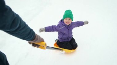 Pov father rides his little child on shovel on rural road at snowstorm. Dad and son having fun on winter outdoor.