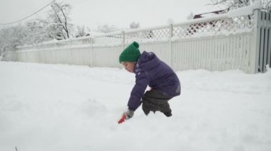 Cute little 5 year child boy shoveling snow after snowstorm in countryside. Winter weather.