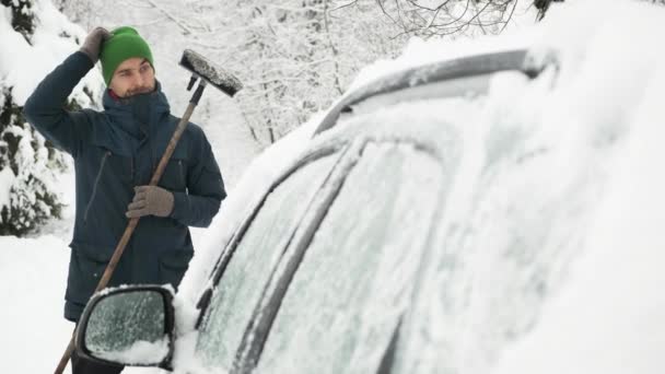 落胆し混乱した男は豪雪の後ブラシで車を覆った 悪天候 自然災害 車を雪からきれいにする — ストック動画