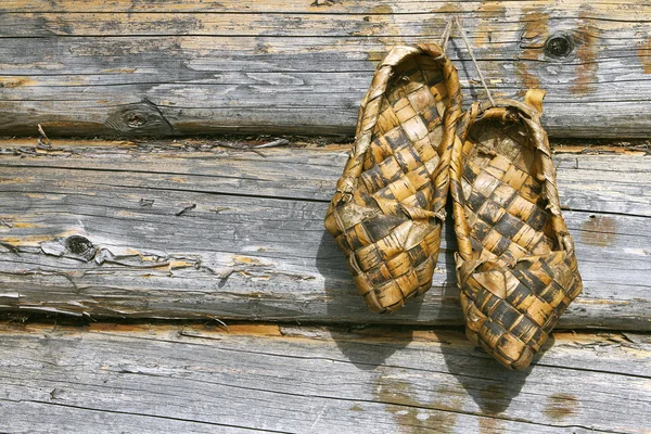 Russische bast schoenen en houten muur — Stockfoto