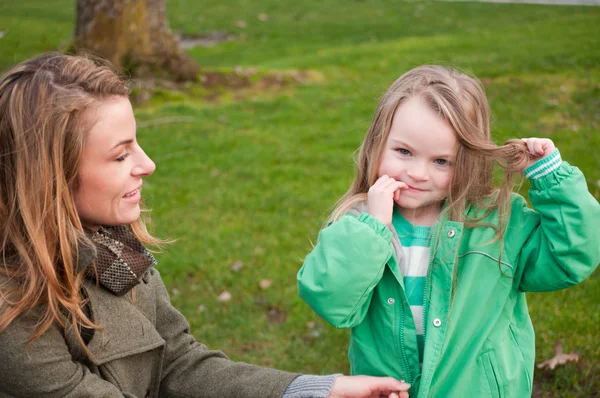 Moeder en schattig klein meisje houden een onderdeel van haar haren — Stockfoto