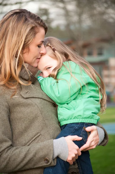 Mother holding shy smiling girl — Stock Photo, Image