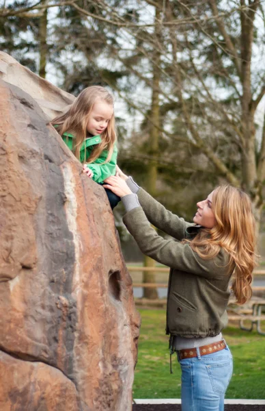 Moeder helpen haar dochtertje te klimmen naar beneden uit een rots — Stockfoto