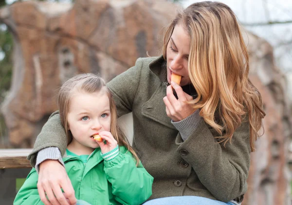 Moeder en dochter met een snack buiten — Stockfoto