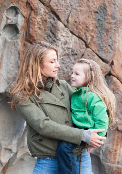 Toddler girl sitting on mother's hip against rock wall — Stock Photo, Image