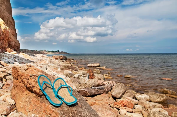 Pair of flip-flops on the stones near the sea — Stock Photo, Image