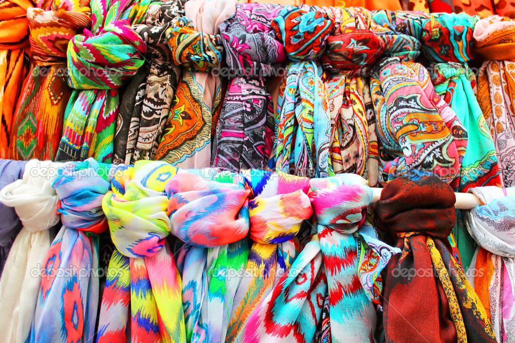 Rows of colourful silk scarfs hanging at a market stall in Tossa