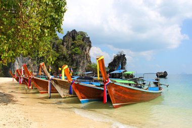 Long tail boat on tropical beach with limestone rock, Krabi, Thailand clipart