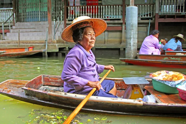 Unidentified woman is sails in the floating market along raft houses at the river Kwai in Kanchanaburi, Thailand.