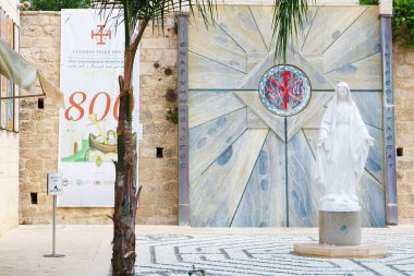 Nazareth, Israel - September 21, 2017: Statue of Virgin Mary next to the Basilica of the Annunciation. The vertical Greek text on the wall in background means 
