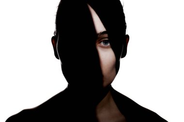 Şirin bir kızın moda stüdyo portresi. Yüzünde sert gölgeler olan genç ve güzel bir kadının silueti. beyaz arka plana karşı.