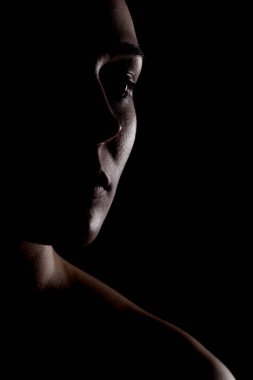 Yandan aydınlık siluet bir resim güzel bir genç kadının karanlık arka planda karşı karşıya