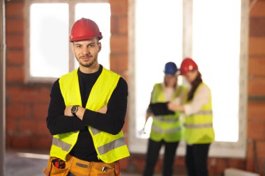 Arka planda çalışan mühendis ekibiyle birlikte bir inşaat alanında çalışan erkek işçi.