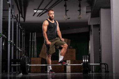 Ağırlık kaldırmaya hazırlanan bir sporcu. Spor salonunda poz veren kaslı bir adam..