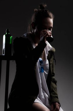 Alkol şişesi ve plastik bardağı olan güzel bir kızın stüdyo portresi..