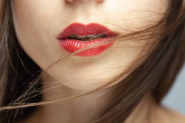 Kırmızı rujlu güzel beyaz bir kızın soyut portresini kapat. Rüzgarlı saçlar yüzünde uçuşuyor.