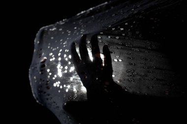 Soyut silüet eller geriliyor ve yarı şeffaf kumaşı arka planda küçük delikler ve ışık ile itiyor