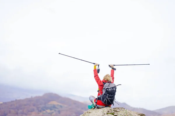 远足的女孩坐在山上的岩石上 手举着远足的柱子欣赏风景 秋天外出旅游及健康生活 — 图库照片