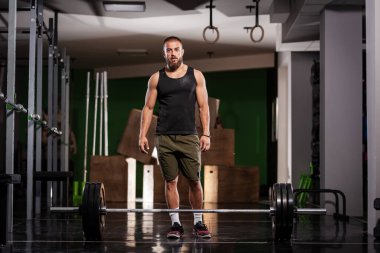 Ağırlık kaldırmaya hazırlanan bir sporcu. Spor salonunda poz veren kaslı bir adam..