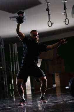 Çok ağır ağırlık kaldıran kaslı bir atletin silüeti. Adam içeride çalışıyor.