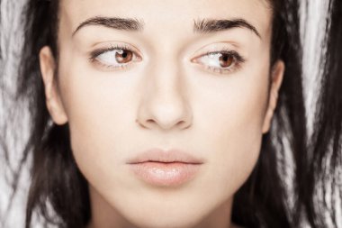 Beyaz arka plana karşı güzel bir genç kızın stüdyo portresi. Yana bakıyor.