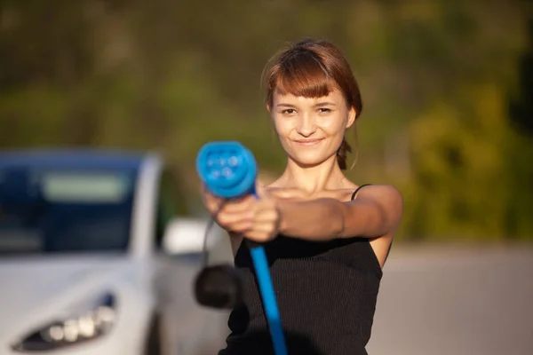 Gyönyörű Fiatal Lány Egy Elektromos Autó Mellett Töltőkábel Elhelyezése Tartása — Stock Fotó
