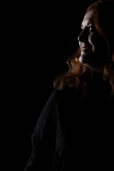 黒の背景に赤い髪の女性の肖像画 影の少女 — ストック写真