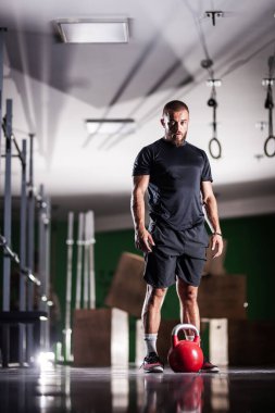 Kettlebell 'le poz veren kaslı bir sporcu. Adam içeride çalışıyor..