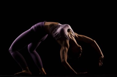Stüdyoda yoga yapan formda bir kız. Yarı siluet yan aydınlatma fitness modeli
