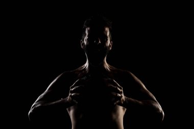 Basketbolcu siyah arka planda topu tutuyor. Yan aydınlatma kaslı beyaz adam silueti.