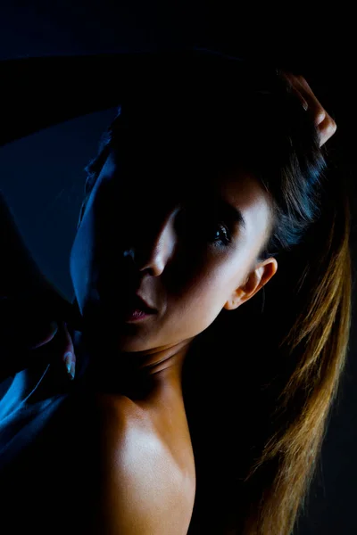 美丽的黑发女孩工作室肖像 侧面在黑暗的背景上闪烁着一半的轮廓 严肃的面部表情 — 图库照片