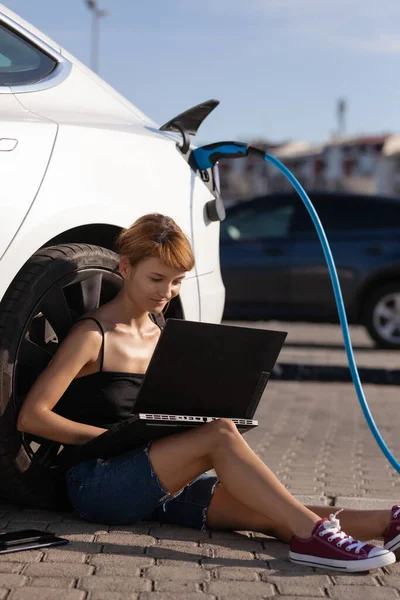 Dziewczyna Czeka Ziemi Kiedy Jej Elektryczny Samochód Się Ładuje Praca — Zdjęcie stockowe